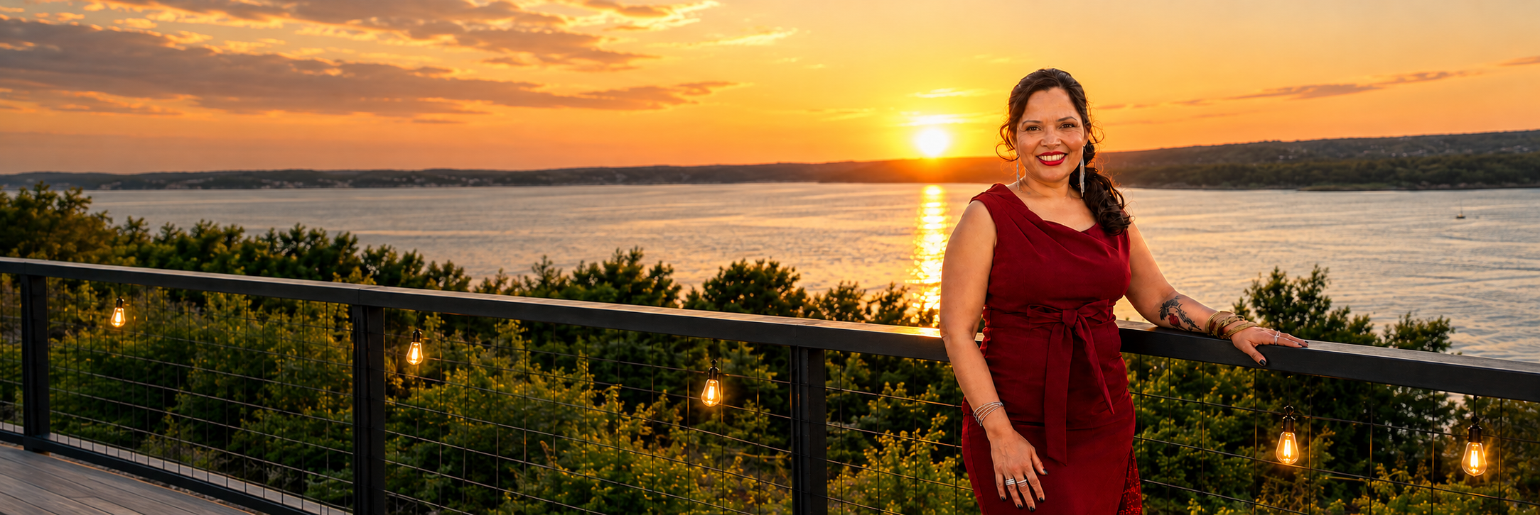 A woman standing by a waterfront at sunset